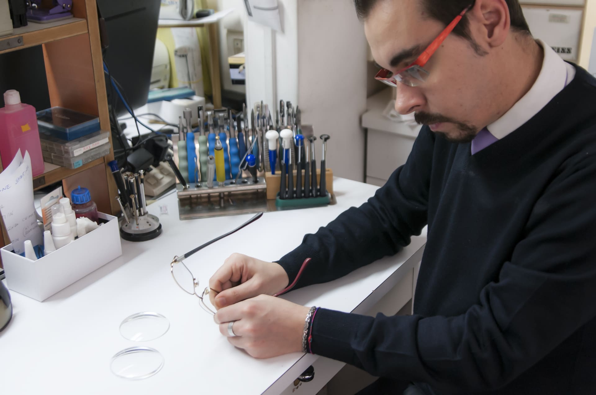 Un uomo che indossa occhiali da vista maneggia con cura un paio di occhiali - Crisafulli Eyewear a Milano
