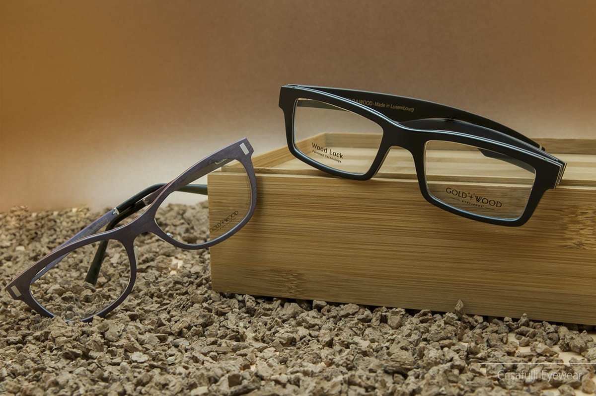 Due paia di occhiali da vista Gold & Wood eleganti sono esposti su una superficie strutturata - Crisafulli Eyewear a Milano